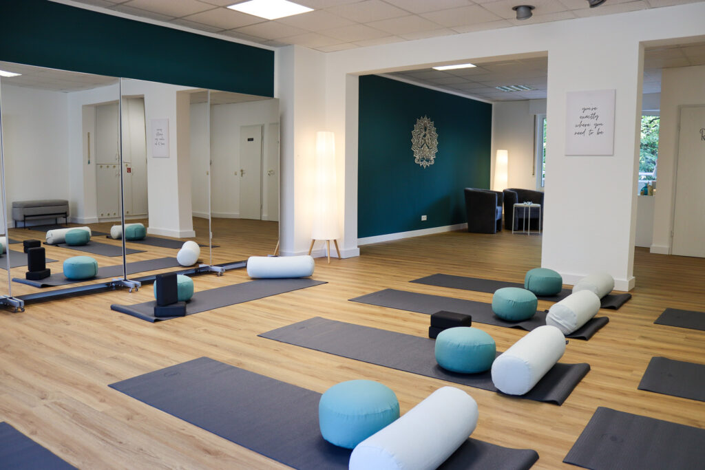 Das VAYANA-Yoga-Studio, in dem Matten und weitere Yoga-Utensilien vor einer Spiegelwand ausgelegt sind.