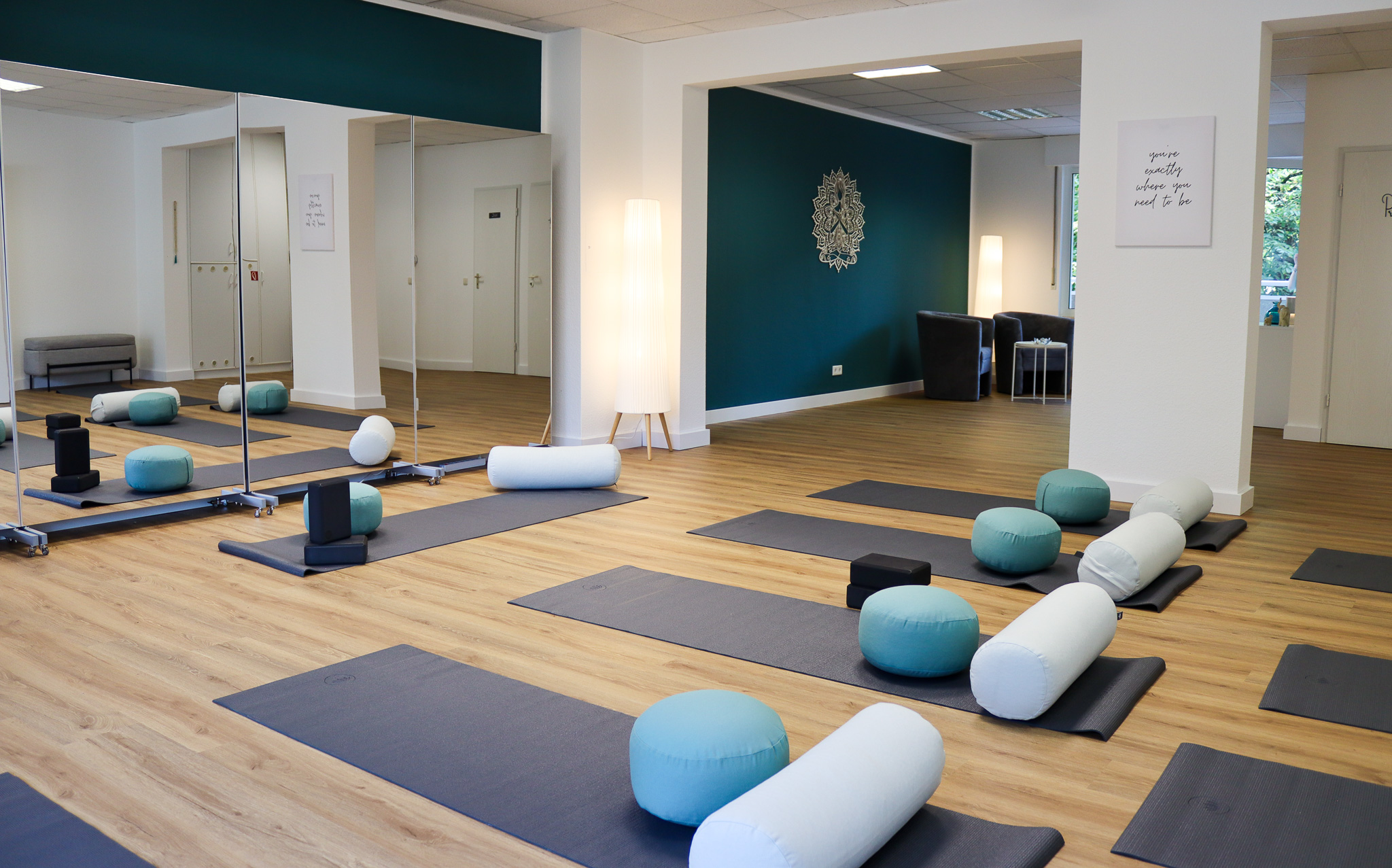 Das VAYANA-Yoga-Studio, in dem Matten und weitere Yoga-Utensilien vor einer Spiegelwand ausgelegt sind.