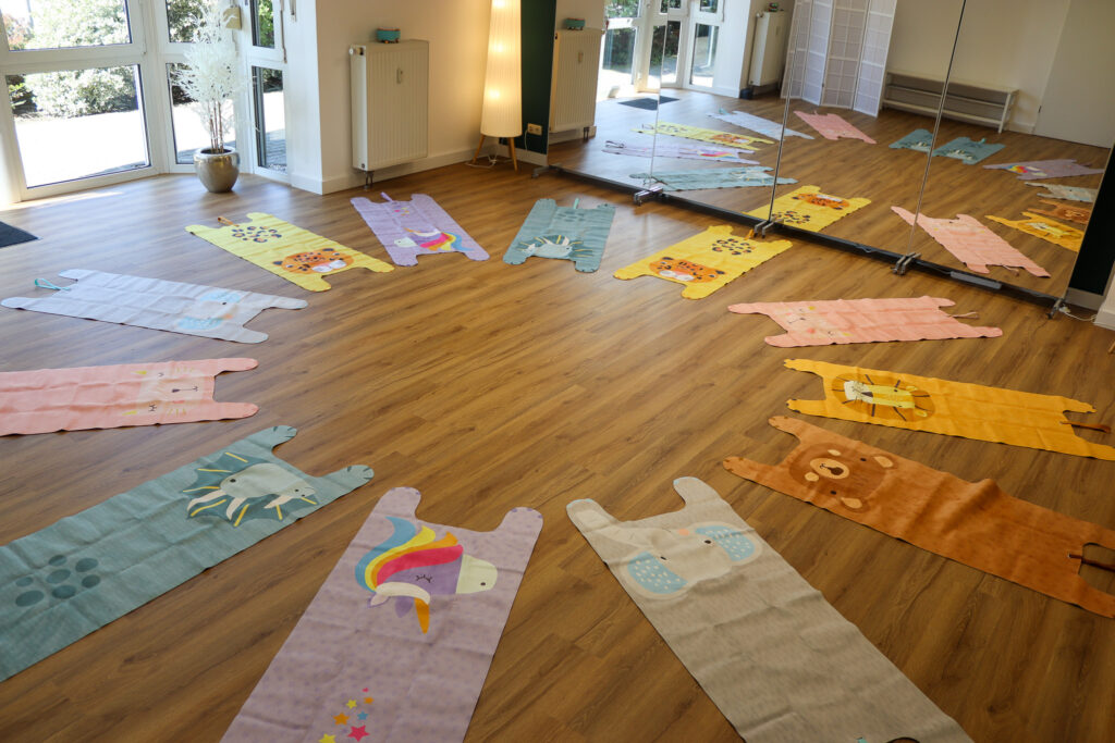 Kinder-Yogamatten in Tierdesigns sind in einem Kreis im VAYANA-Yoga-Studio ausgelegt.